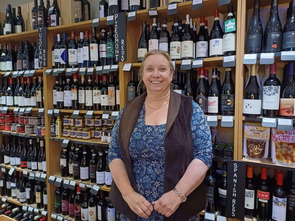 A woman standing in front of a wine display at Wined up here
