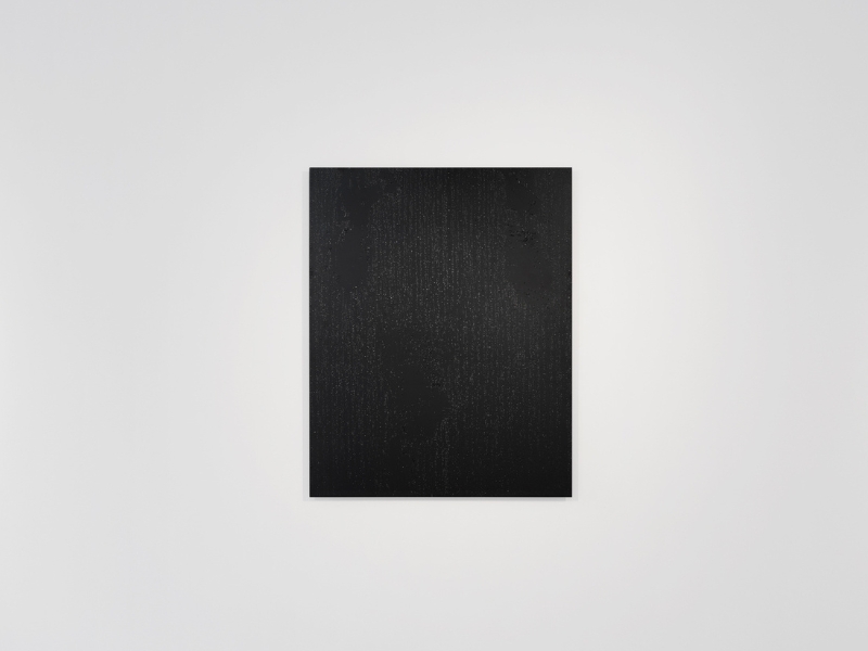 A black alluminium artwork called User_01 by Prem Sahib with resin splatters that resemble sweat droplets on a wall. 
