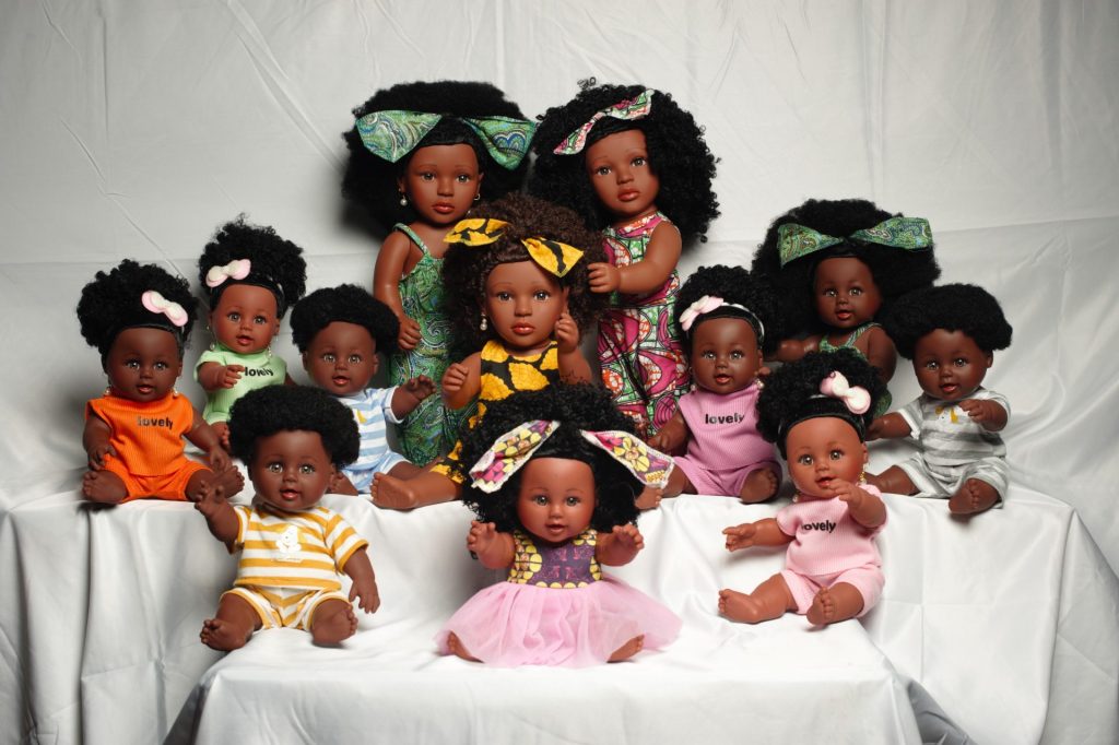 An array of 12 black dolls with varying afro curls and brown skin tones.