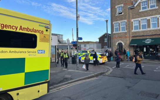 Ambulance and police car parked outside Mortlake train station with police officers visible