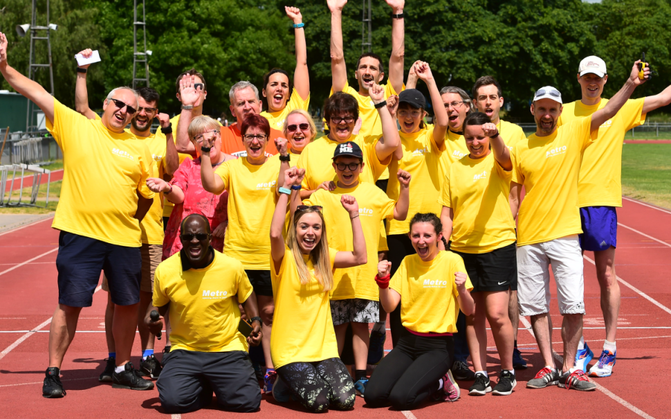 People at Metro Blind Sport pose for a group picture on a race track.