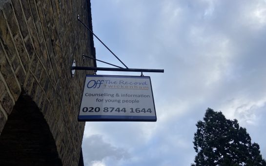 Off the Record sign outside the building. White sign with blue writing saying Off the Record Twickenham, counselling and information for young tomorrow, 020-874-41644