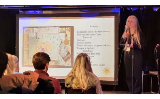 a picture from the mental health charity event run by Shine Bright UK, showing a woman on stage reading a poem called 'Longing'