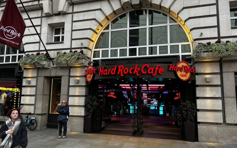 picture of the outside of Piccadilly Hard Rock Cafe.The Name is in bold red writing the brick is grey.