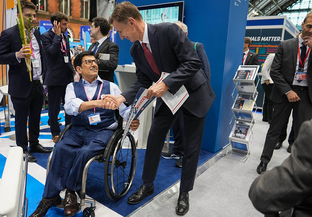 Jeremy Hunt shakes hands with wheelchair user at Conservative Party Conference 2023.