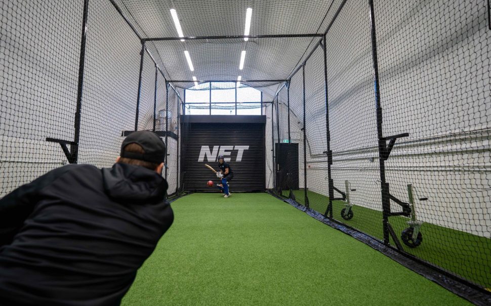 Callum Jackson former England cricketer and NET company owner bowls a ball towards a cricketer in his single laned indoor practice facility