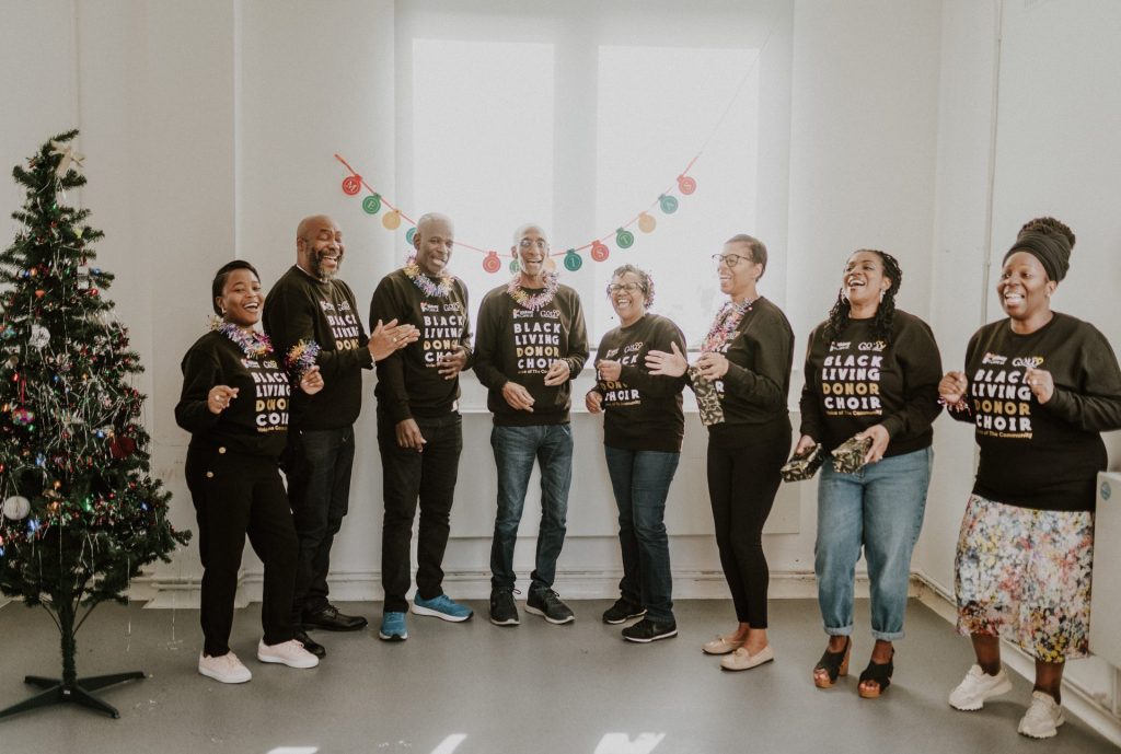 Members of the Black Living Donor Choir sharing smiles and laughter mid-performance