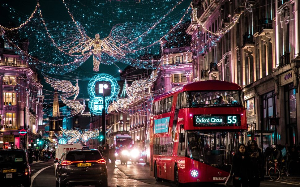 Image shows London Christmas lights lite up with a double decker bus on the right hand side.
