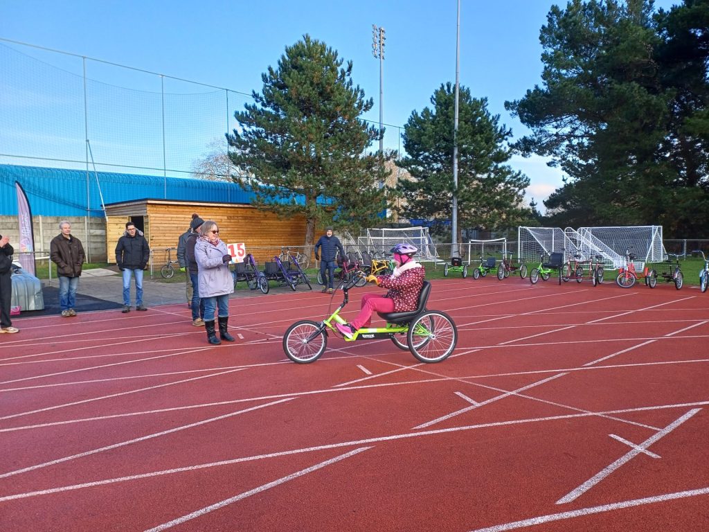 Jessica, a woman, completing her fifteenth lap on a recumbent tricycle.