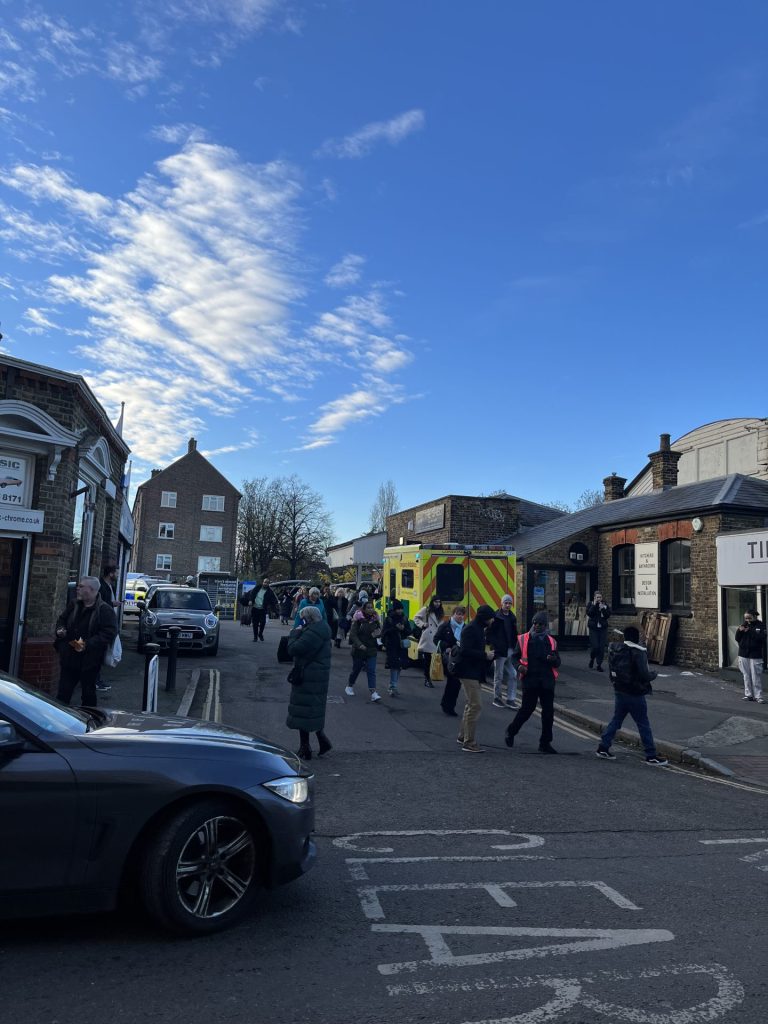 Passengers leave Mortlake station after being escorted off the train with an ambulance parked outside