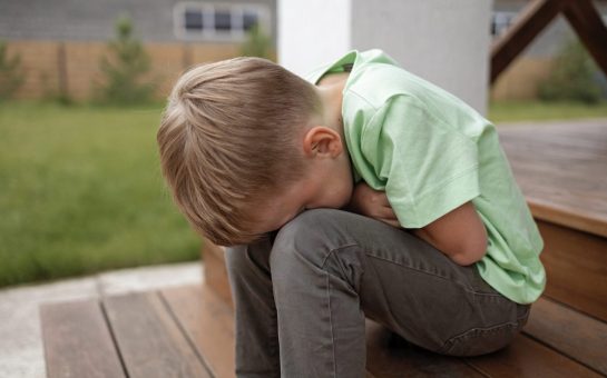 Photo of a sad child hiding his face