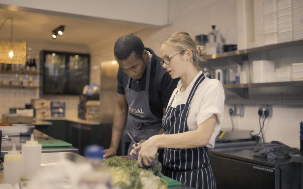 Two people prepping vegetables in a kitchen.