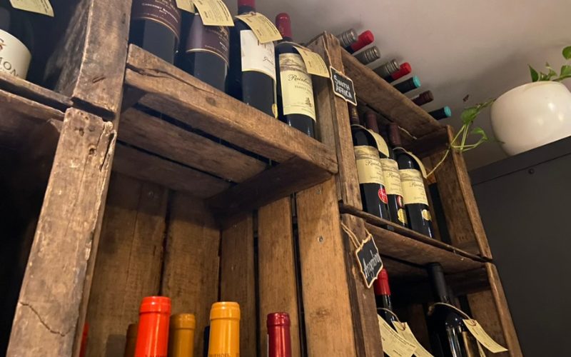 A variety of wine bottles on rustic, wooden shelves in Humble Grape - a restaurant in Battersea.