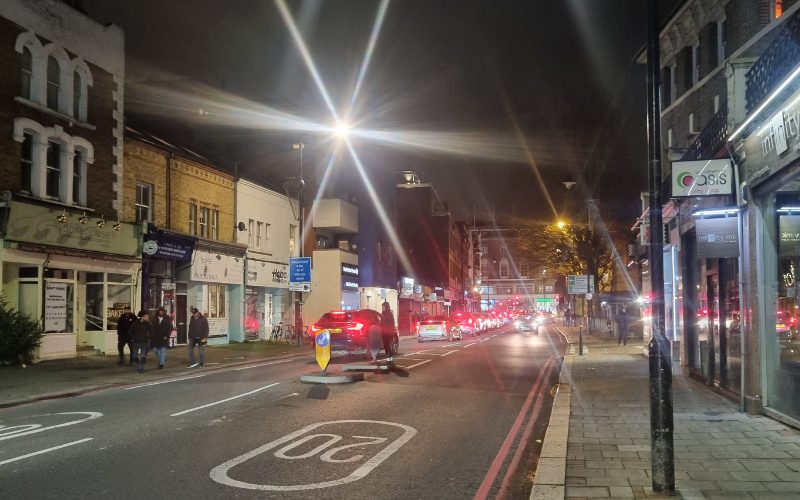 An image of Putney at night with cars and streetlights shining brightly.