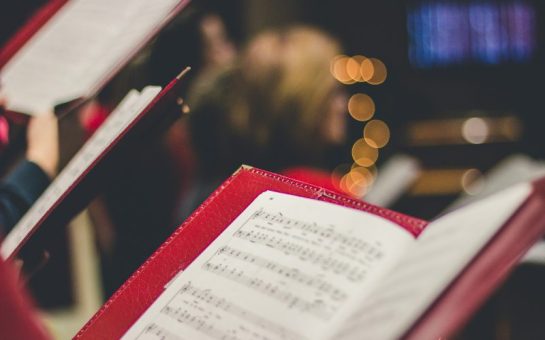 Picture of a red music sheet book with a blurred Christmas tree in the back