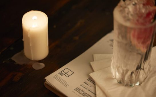 The corner of a menu saying table&candle can be seen with a candle melting in the far corner.