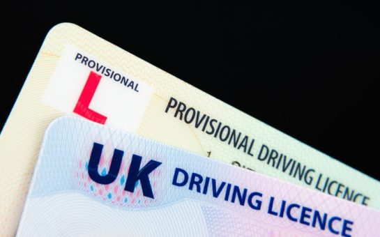 The left corners of a UK driving licence and a provisional driving licence overlaid on one another. The picture has a black background.