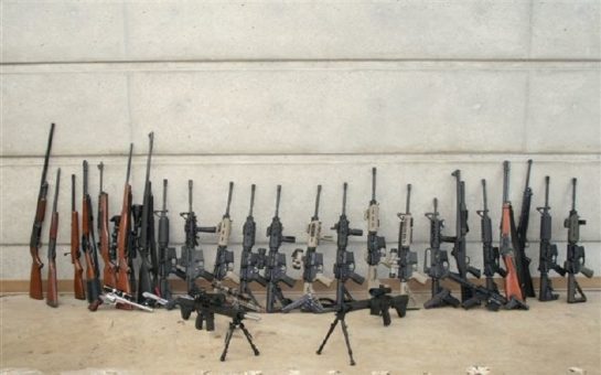 A collection of firearms laid out against a wall