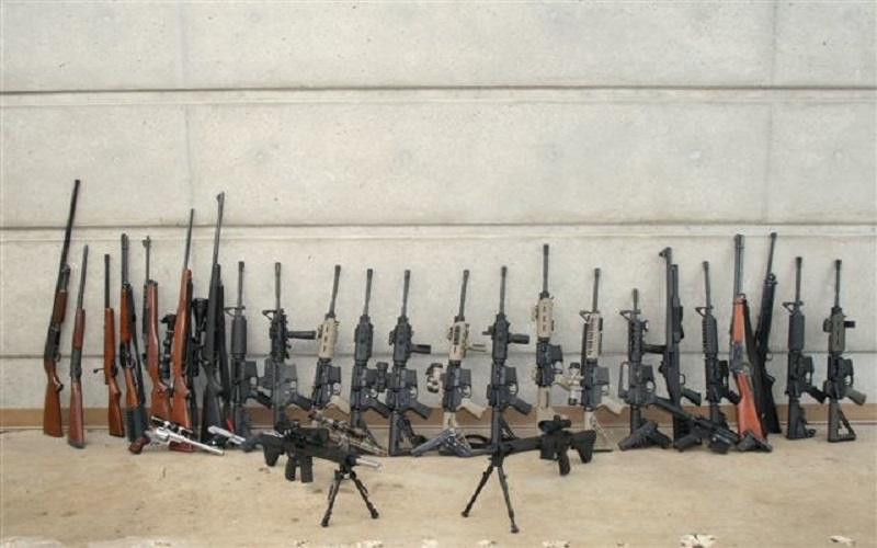 A collection of firearms laid out against a wall