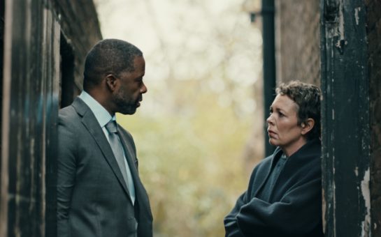 Olivia Colman stands next Adrian Lester either side of a doorway in a shot from the film Before Our Eyes. They look serious.