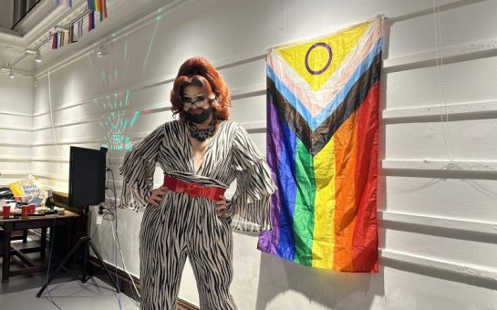Photo of drag queen Beary Poppins in front of the LGBTQ+ flag.