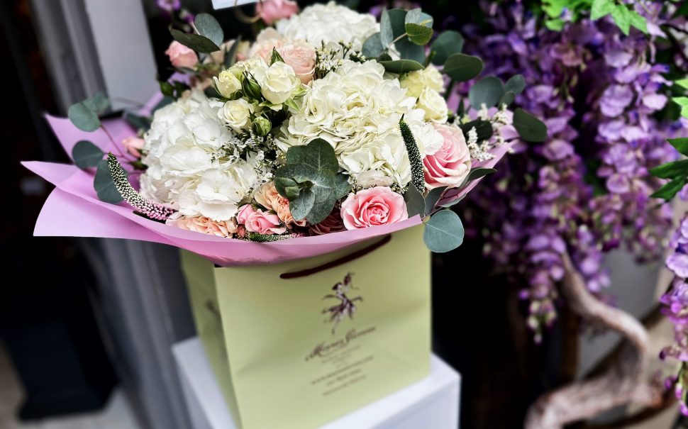 A stunning Moysey Stevens boquet outside the Belgravia store. The flowers are primarily pink and white roses, wrapped up in light pink paper.