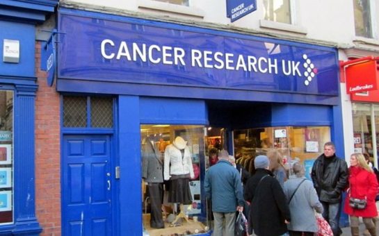 A Cancer Research UK shop in Worcester with a queue of people standing outside it.
