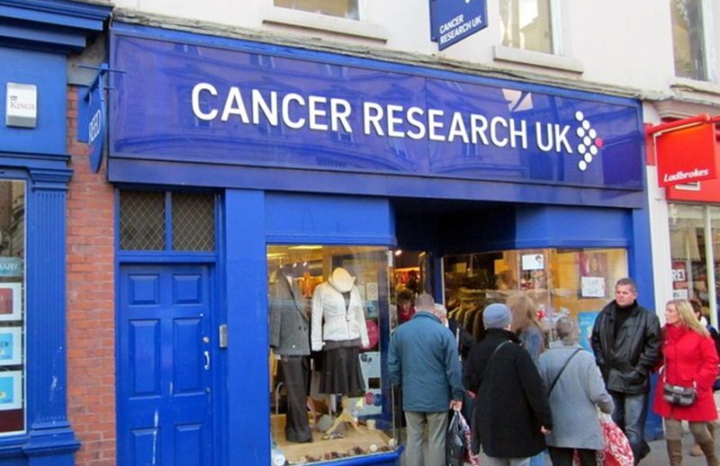 A Cancer Research UK shop in Worcester with a queue of people standing outside it.