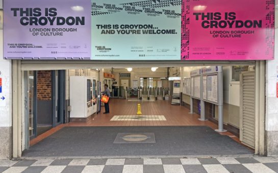 Featuring Croydon station entrance with the barriers in the background and posters advertising this event hanging above