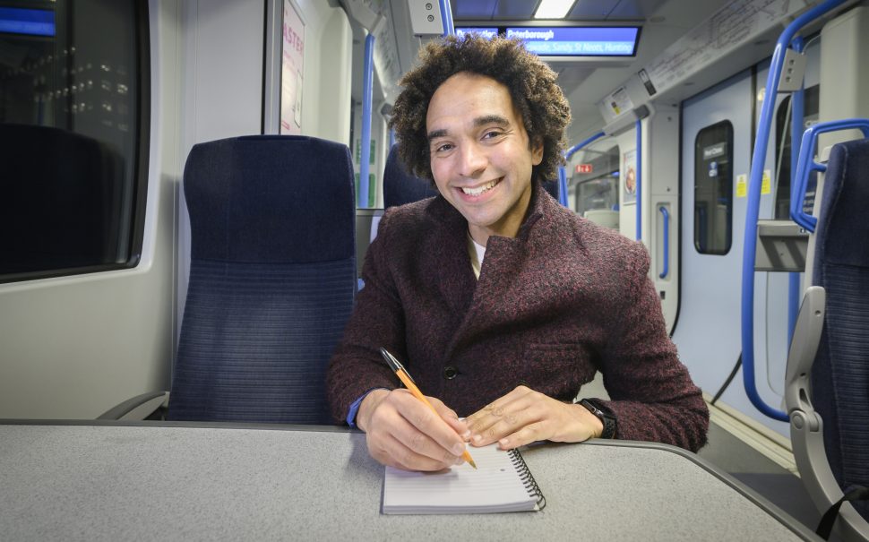 Joseph Coelho, award-winning children's author on a Thameslink train writing poetry to promote their new competition to encourage 5-13 year olds to write.