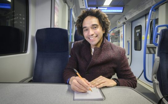 Joseph Coelho, award-winning children's author on a Thameslink train writing poetry to promote their new competition to encourage 5-13 year olds to write.