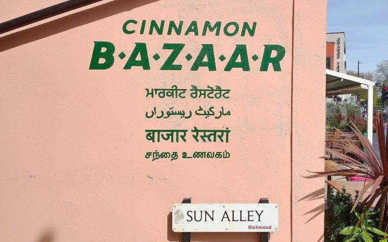 Pink painted side of restaurant with name Cinnamon Bazaar and Richmond street sign