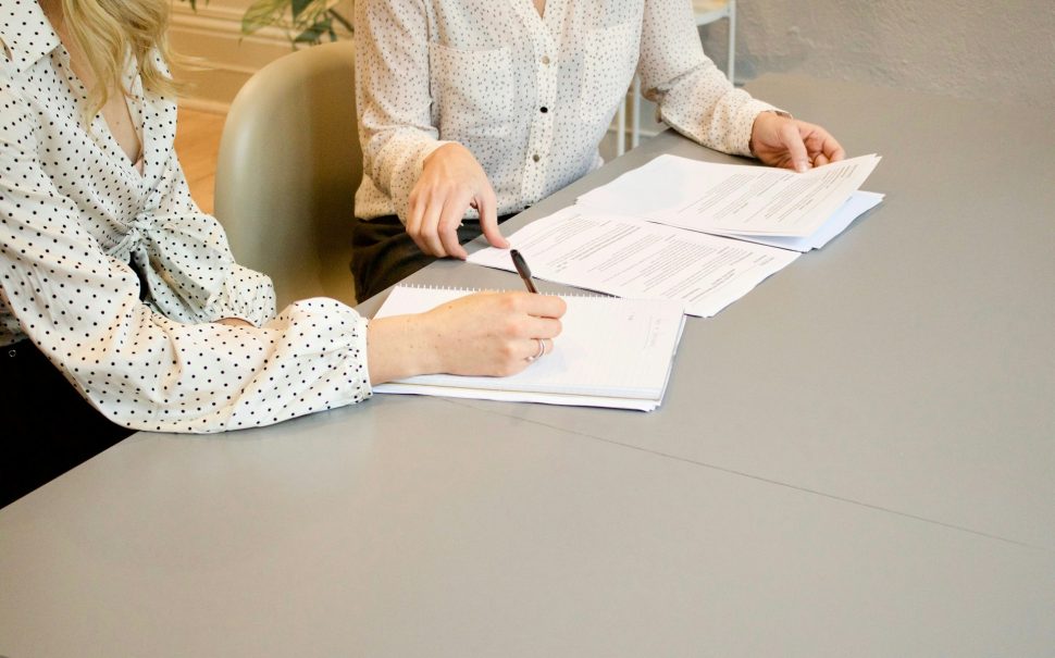 Two women signing some pieces of paper