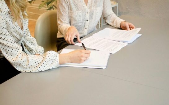 Two women signing some pieces of paper