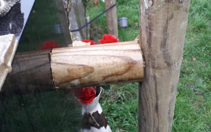 Affected memorial of Vanessa Jux and her beloved mother. The image shows a wooden pole planted into the ground, touching the gravestone.