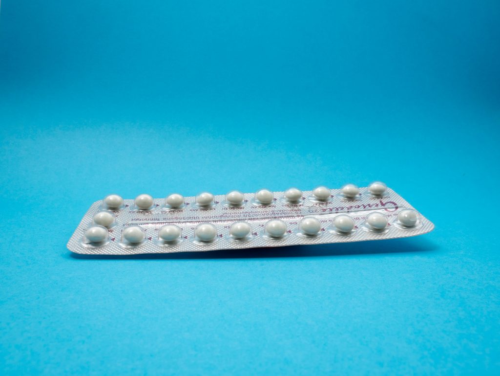 A full contraceptive pill packet pictured on a blue background.