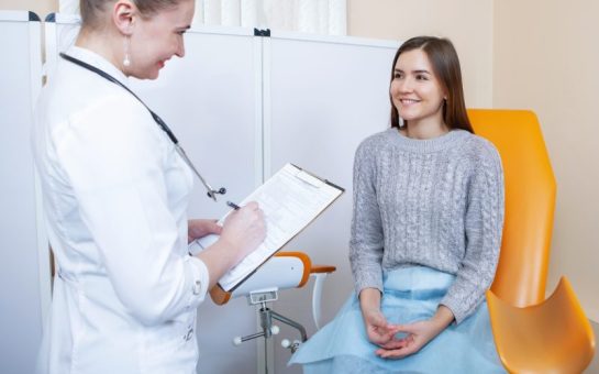 There is a gynaecology doctor talking to a patient in a grey jumper