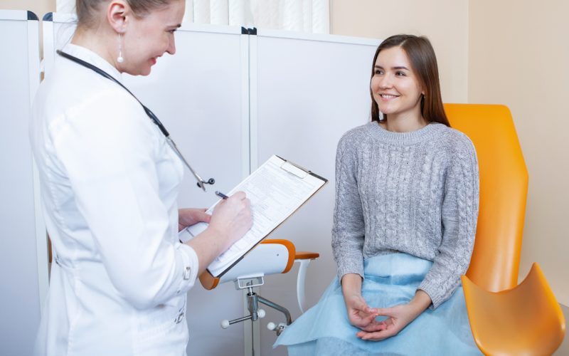 There is a gynaecology doctor talking to a patient in a grey jumper