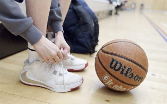 Basketball next to a child tying their trainers