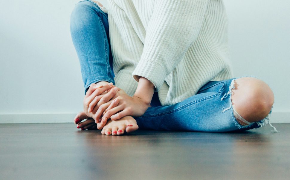 Picture shows woman in discomfort sitting on the floor.