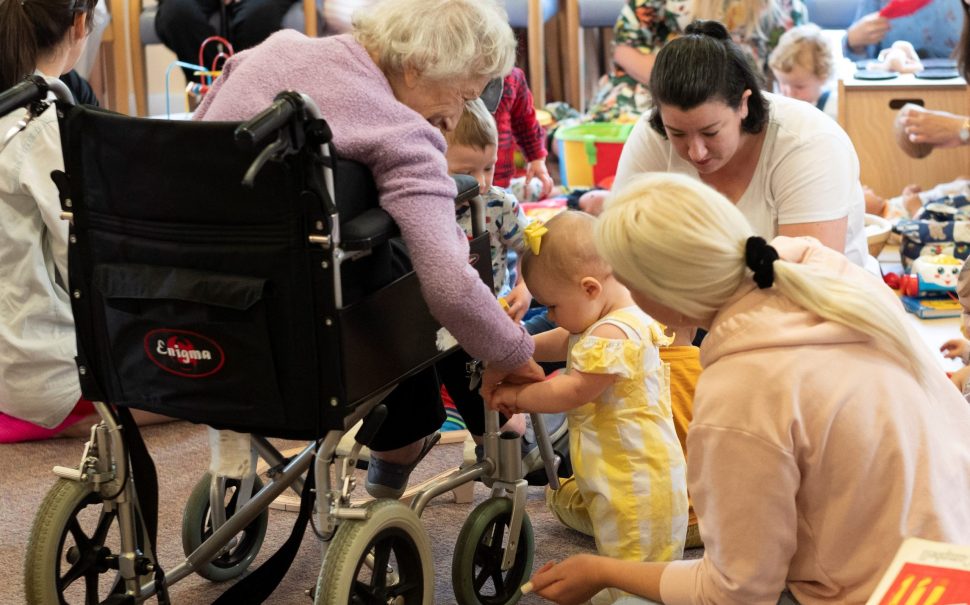 A toddler holding onto a wheelchair at Baby and Toddler intergenerational group