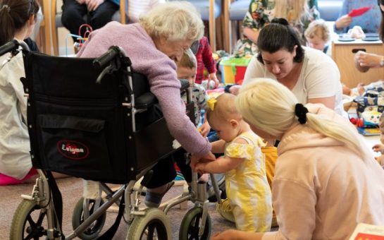 A toddler holding onto a wheelchair at Baby and Toddler intergenerational group