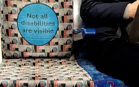A grey seat on the London Underground that says "Not all disabilities are visible"