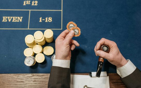 Person holding a poker chip and tobacco pipe