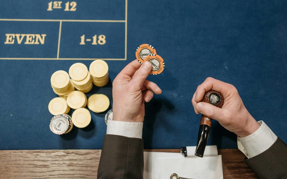 Person holding a poker chip and tobacco pipe