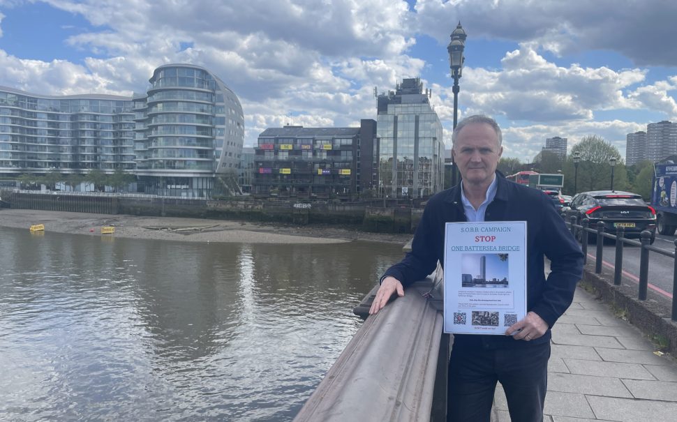 STOP THE TOWER: Petition leader Rob McGibbon stands on Battersea Bridge in front of the current Glassmill building where protest banners have been placed by residents in the block of flats next door. (Image credit: RobMcGibbon_TheChelseaCitizen)