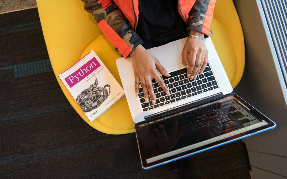 Woman programming with a Python textbook