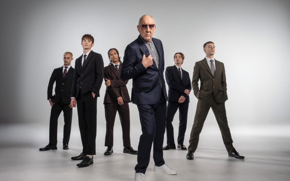 Five dancers and Pete Townshend, a 79-year-old white man, standing and facing the camera in suits from The Who ballet