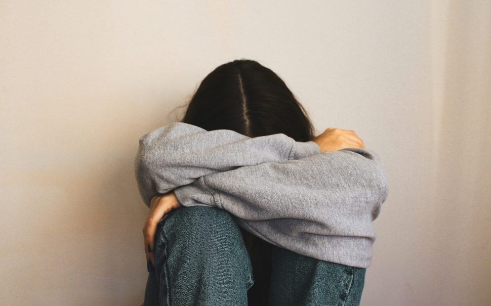 Teenager sadly sits in a corner