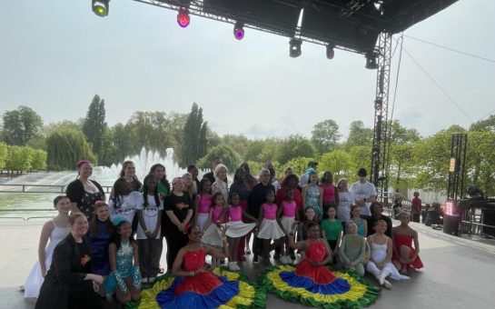 A dance group occupy the stage at Strictly Wandsworth, posing and smiling for the camera.